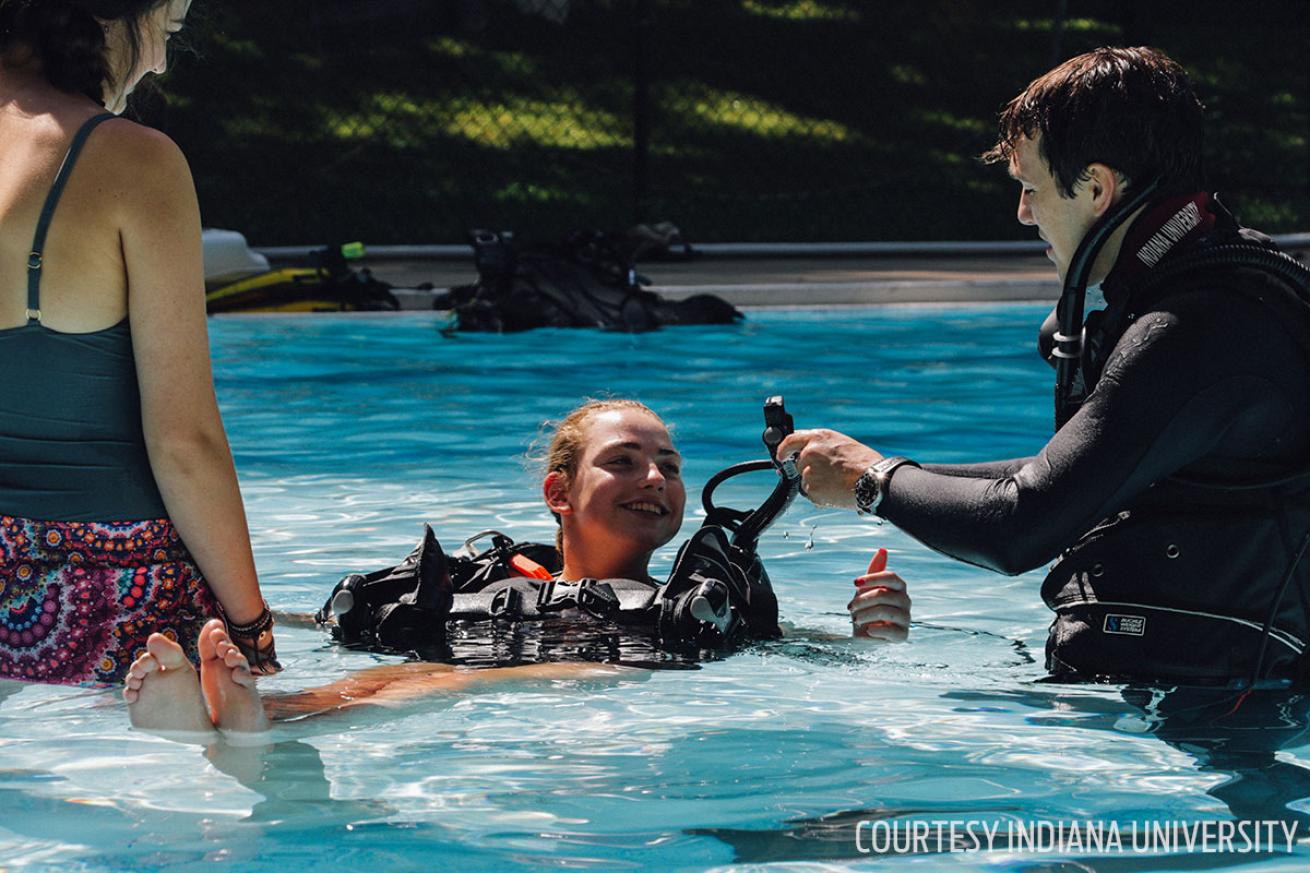Camper getting into scuba diving gear for training