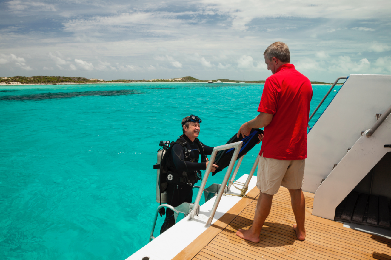 Male in scuba gear climbing down a ladder from a boat