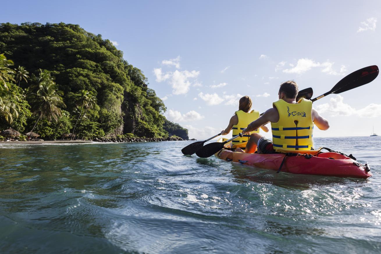 Couple kayaking in the ocean by a beach