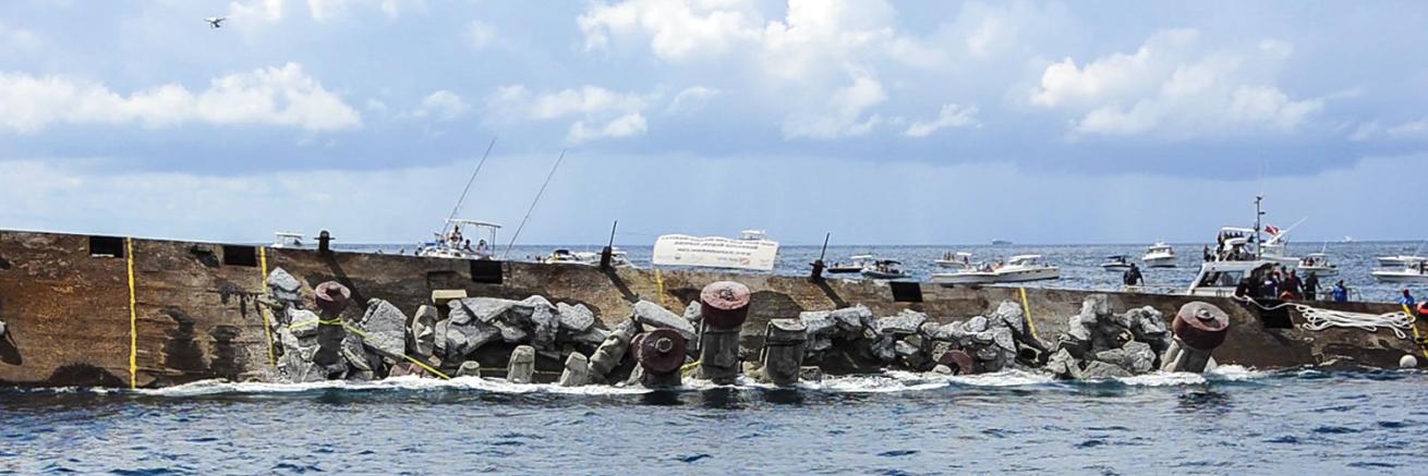 Statues intended for an artificial reef fall off of a barge.