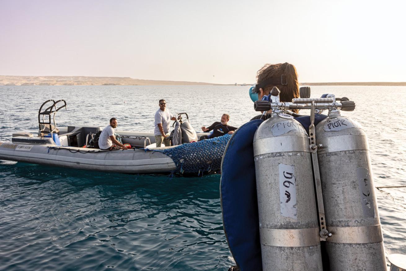 a tech diver gets ready to board a boat at sunset