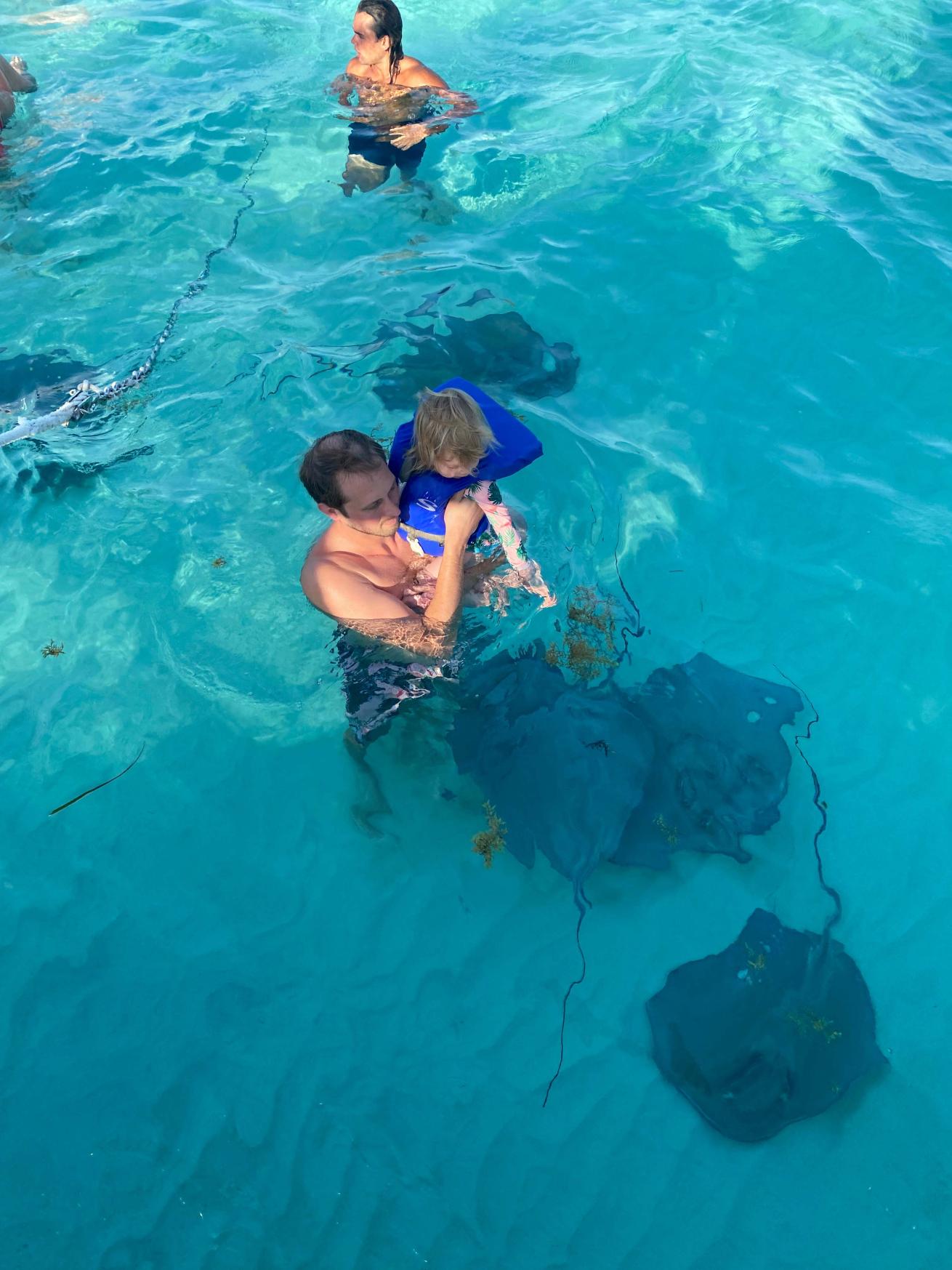a man and his daughter surrounded by stingrays