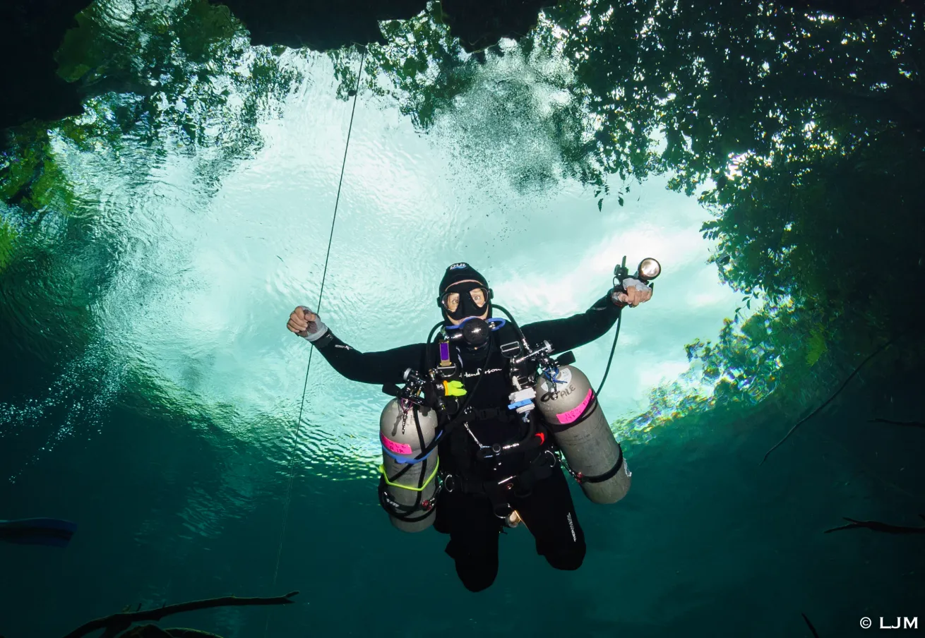 A diver follows a guideline in a dimly lit cavern, emphasizing its role as a lifeline for navigation and safety.
