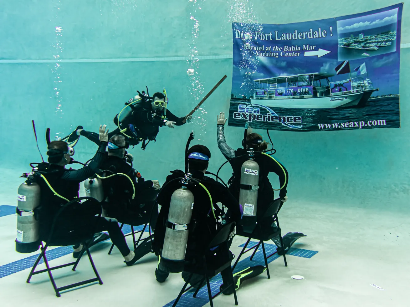 Scuba divers in chairs under water