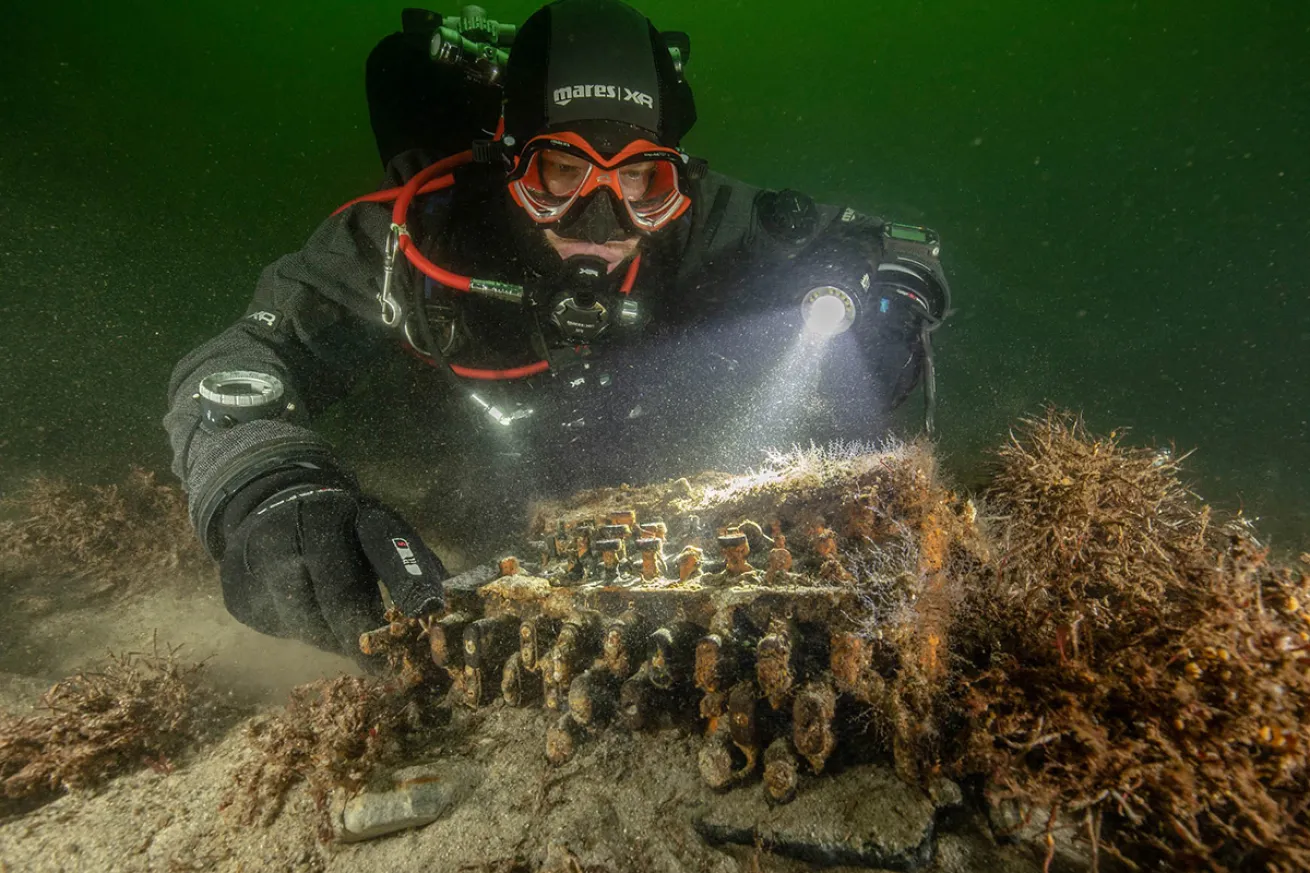 A diver hovers over the newly discovered Enigma machine in the Baltic Sea.