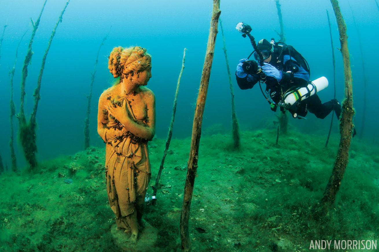 Underwater photo of diver in forest and statue Ohio