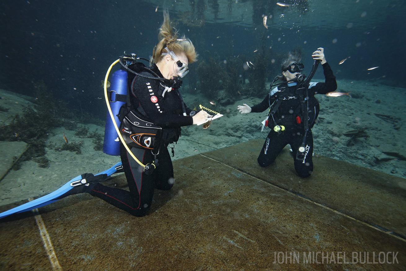 Scuba divers write down underwater notes at Blue Grotto for a ScubaLab gear test