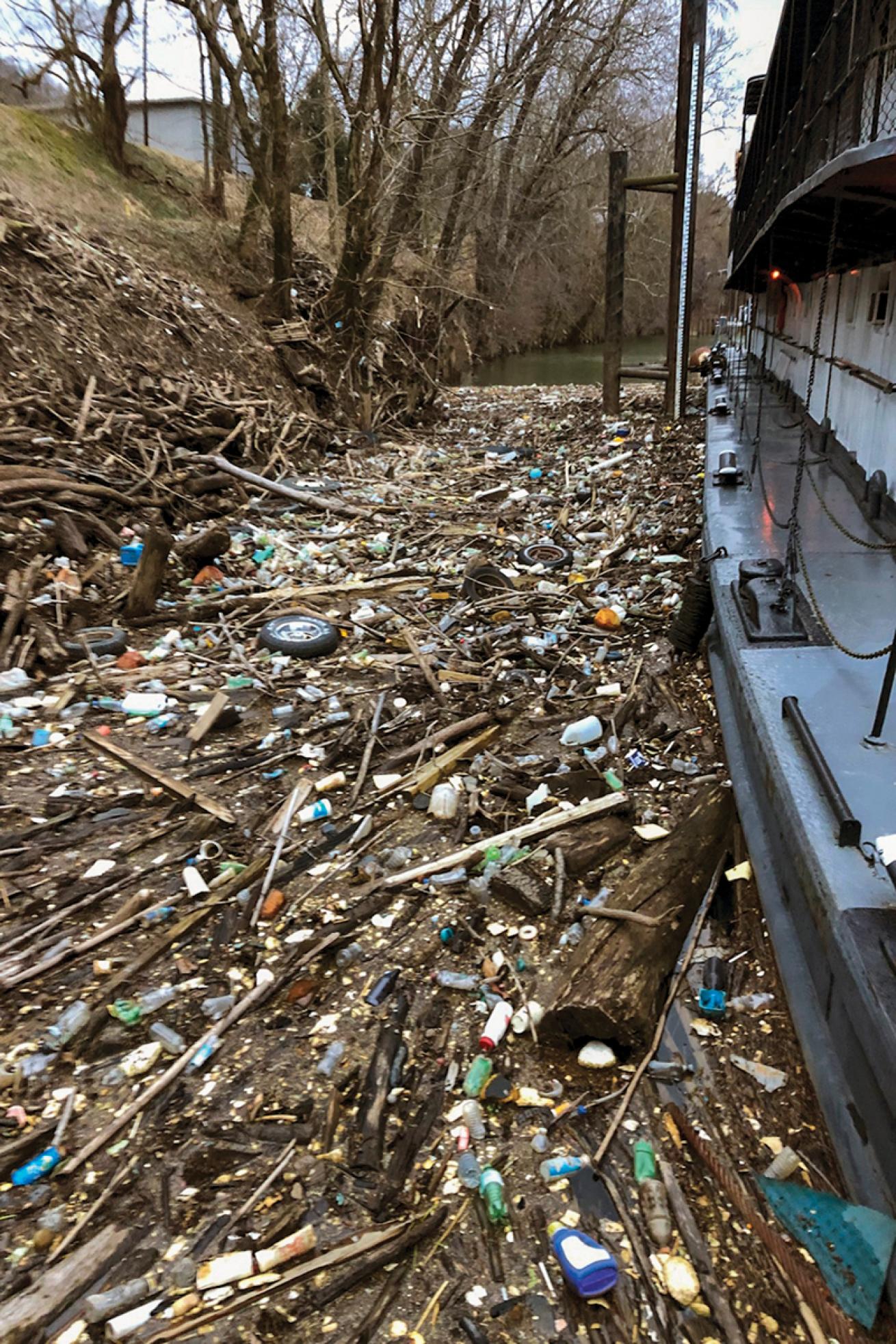 boat pushes through litter crowding riverbank