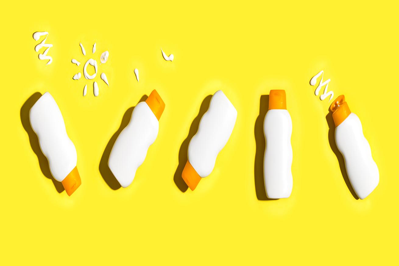Sunscreen bottles against bright yellow background.