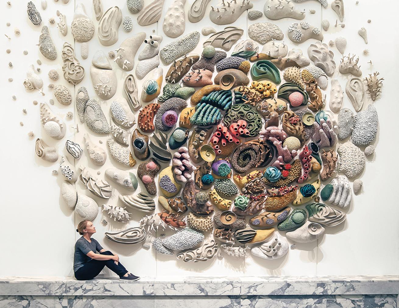 Artist Courtney Mattison sits in front of ceramic coral installation in the U.S. embassy in Indonesia