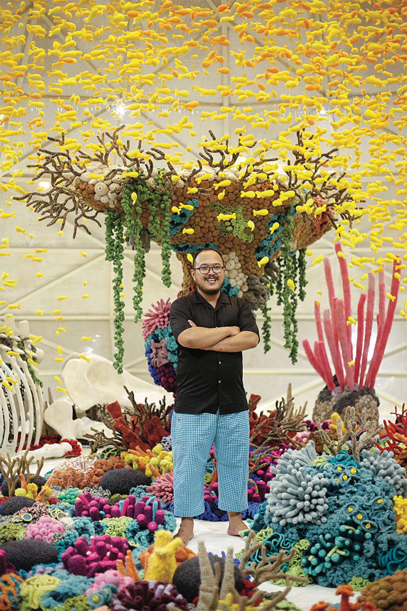 Indonesian artist Mulyana stands in one of his knit coral installation