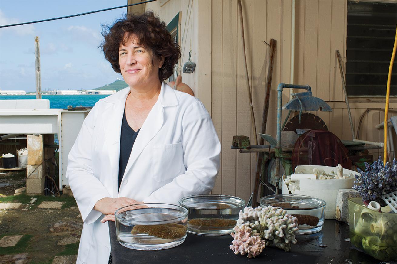 Dr. Mary Hagedorn stands with coral samples in a lab.