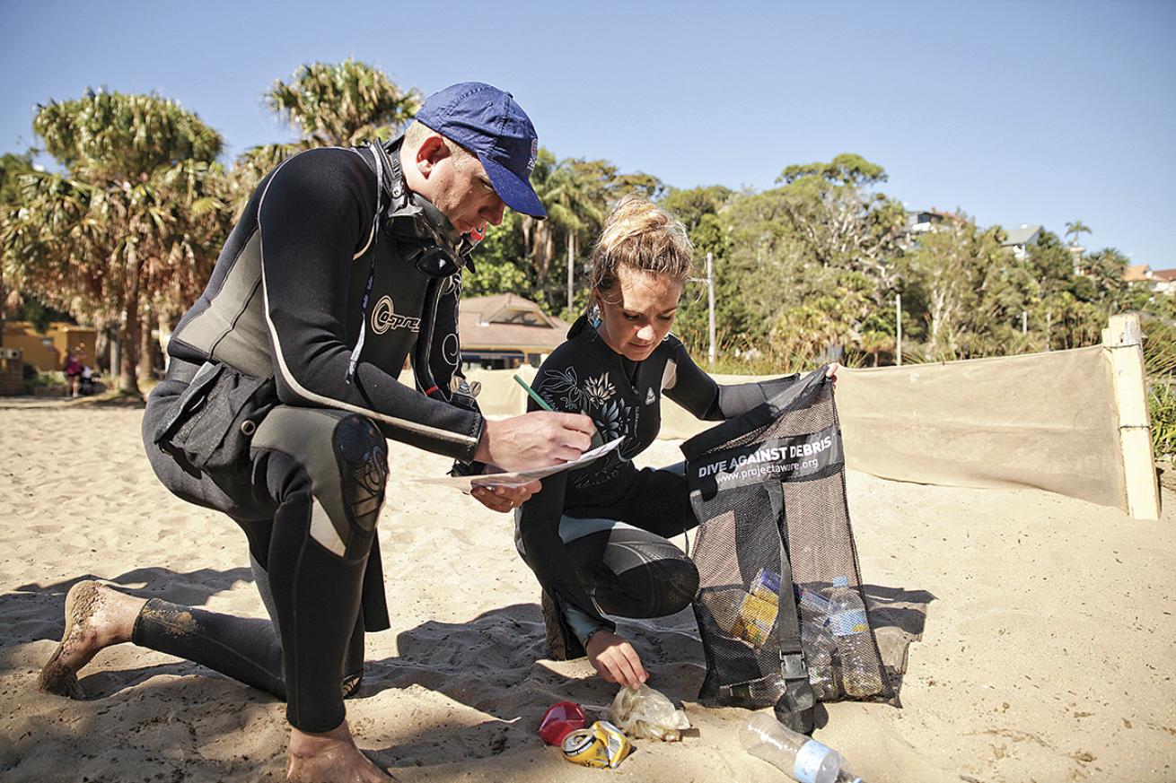 Two divers collect trash on the beach