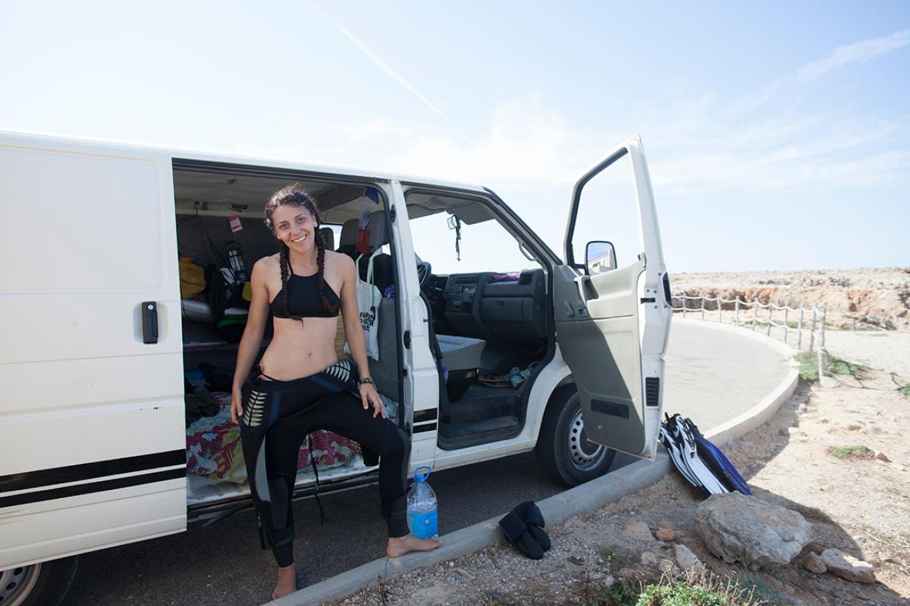 Diver stands by a parked van full of scuba equipment