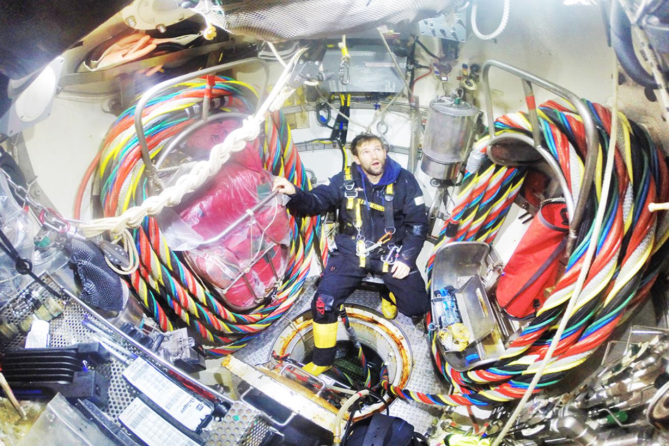 A saturation diver sits among air-supply cords .
