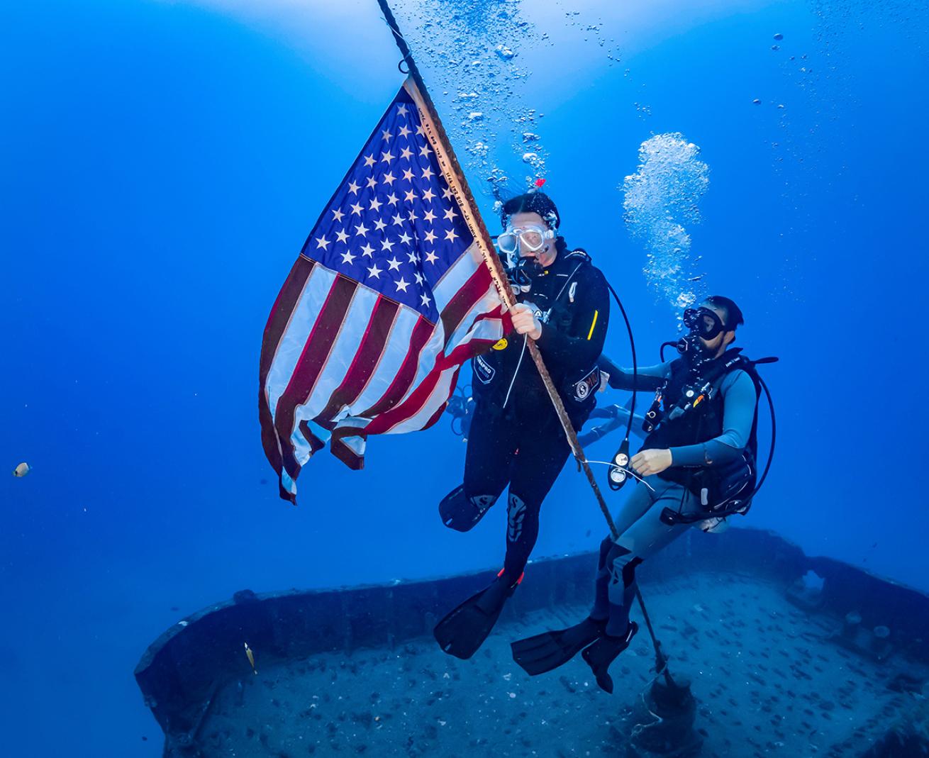 Diver raises us flag on the stern of the Sea Tiger