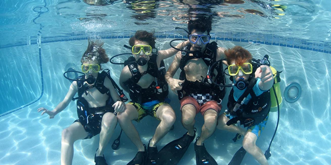 Group of kids scuba diving in a pool.