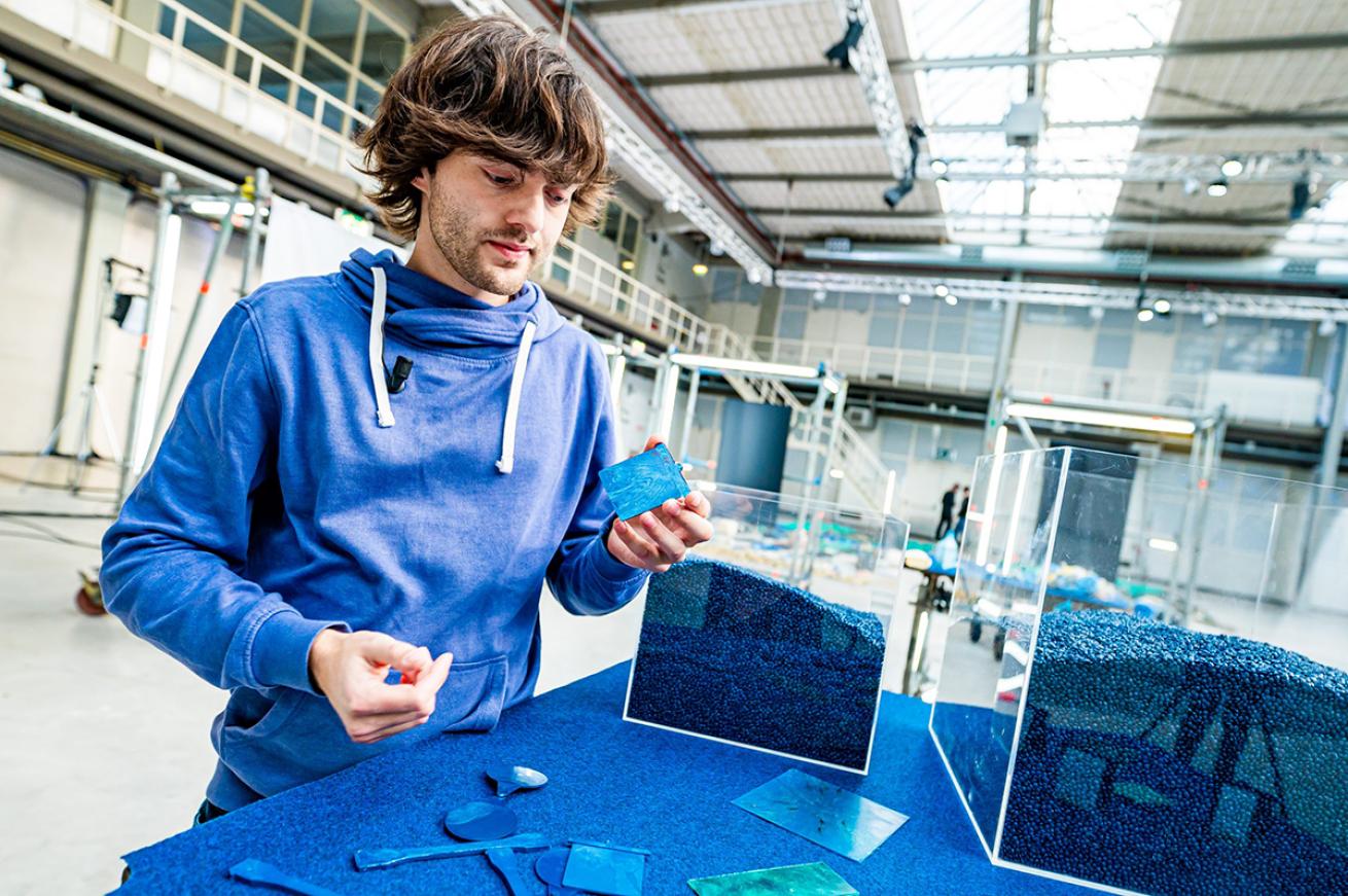 Boyan Slat holds a thin blue strip of recycled plastic