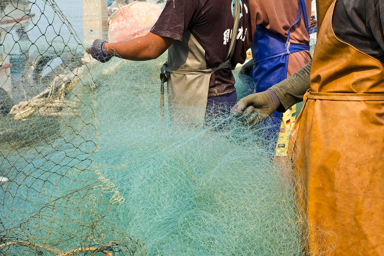 Fishermen pull on a bottom trawling net