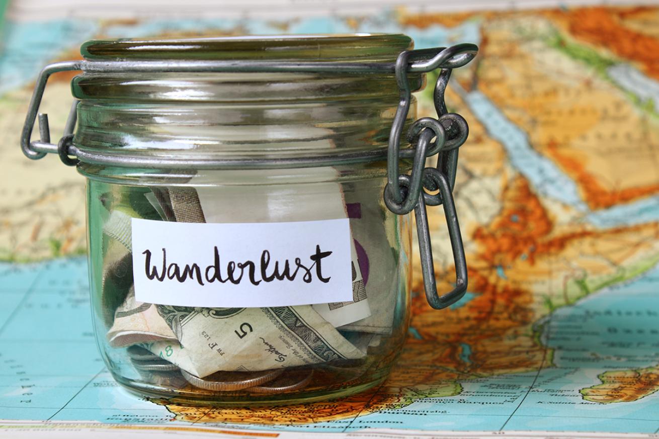 Jar of cash labelled &quot;Wanderlust&quot; sits on a world map