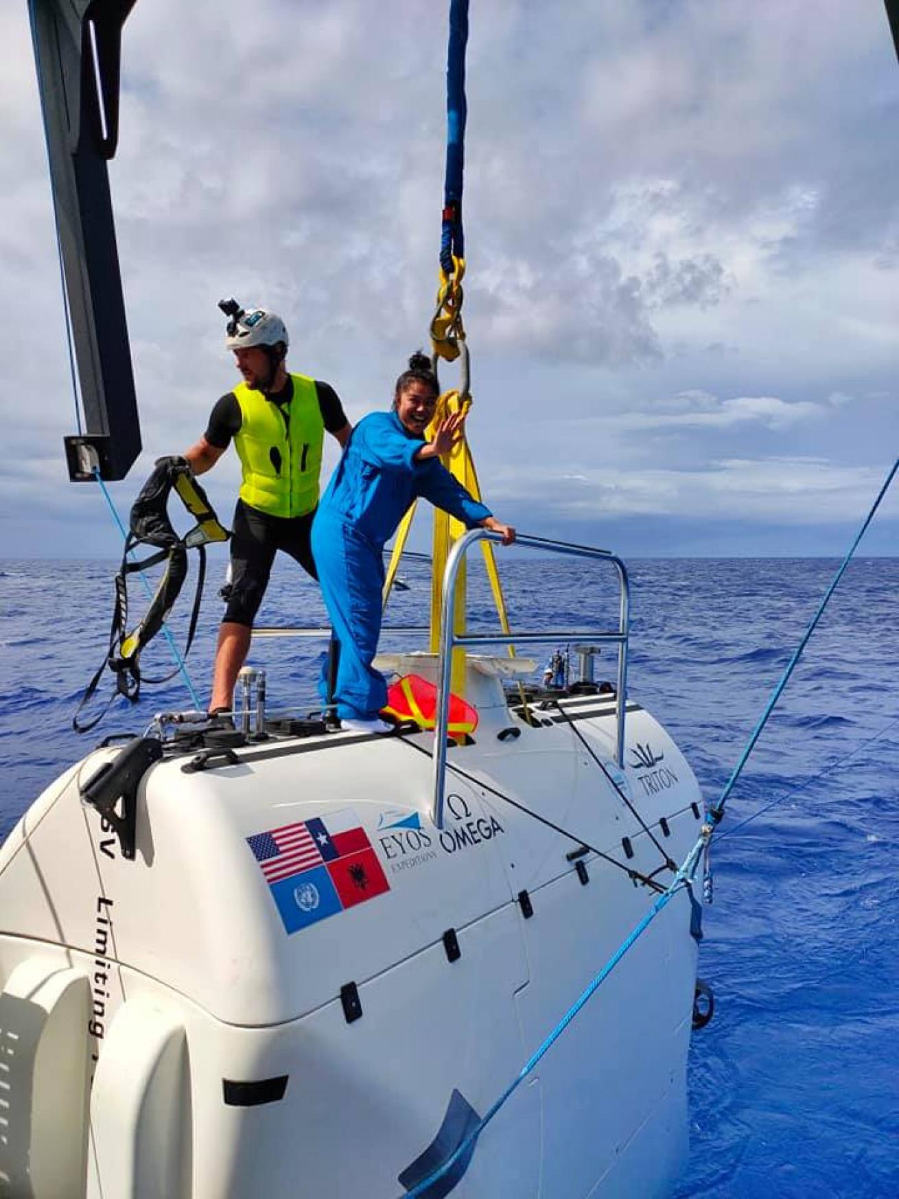 Yamase stands on top of the submersible as it floats partially supported in the water.