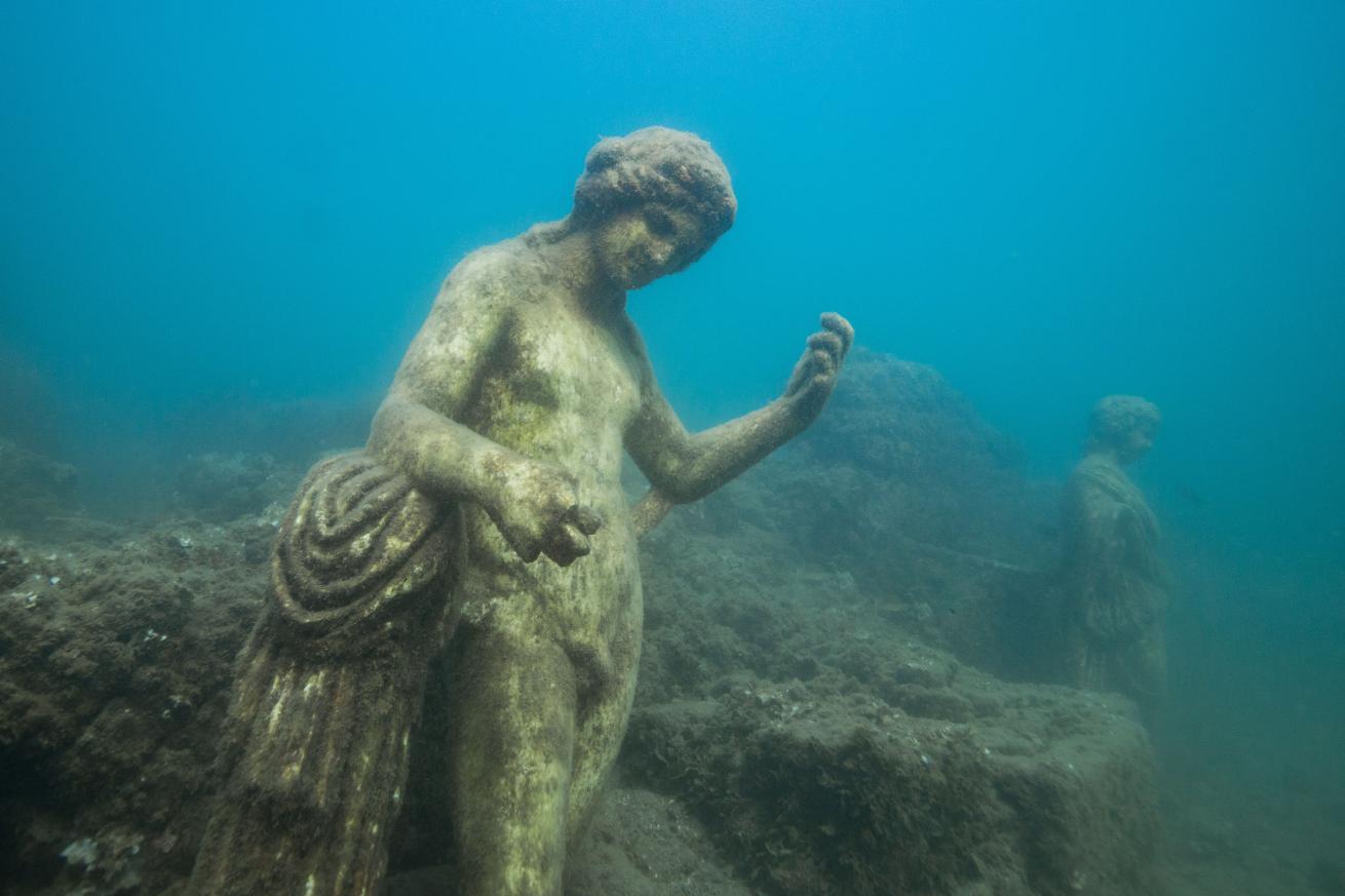 A statue of a female figure sits underwater.