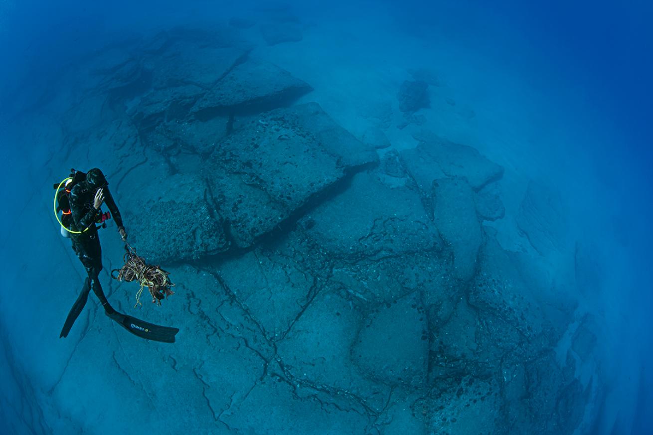 Diver ascends holding marine debris