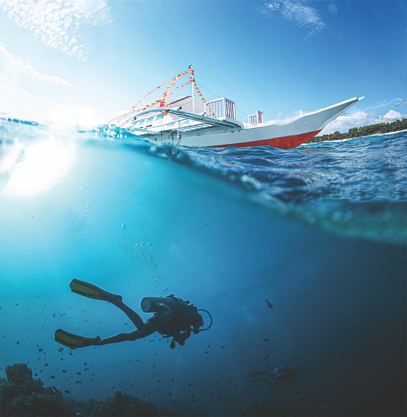 Underover shot of a diver swimming toward a liveaboard