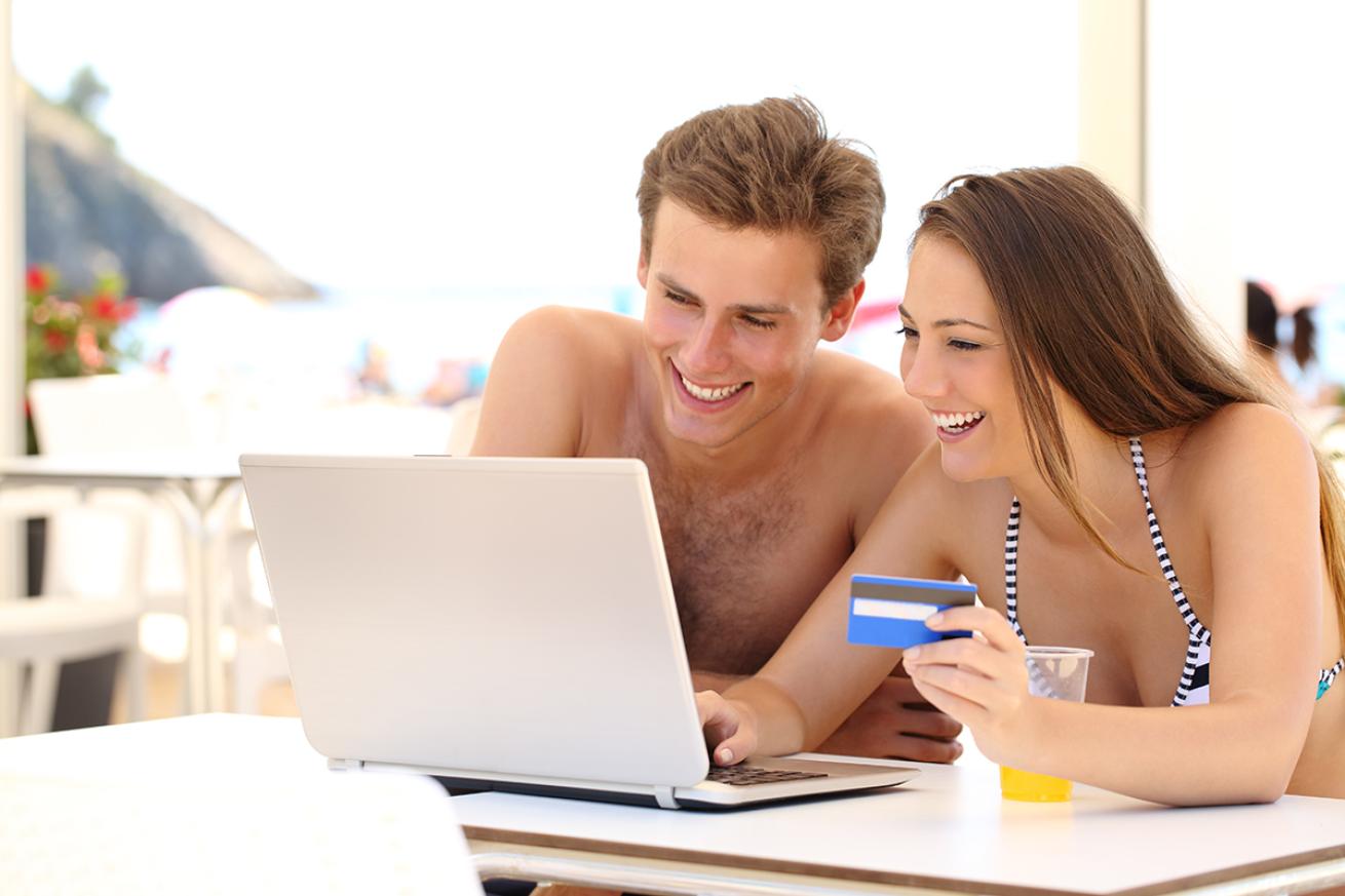 Smiling couple in swimsuits shops online at a beach