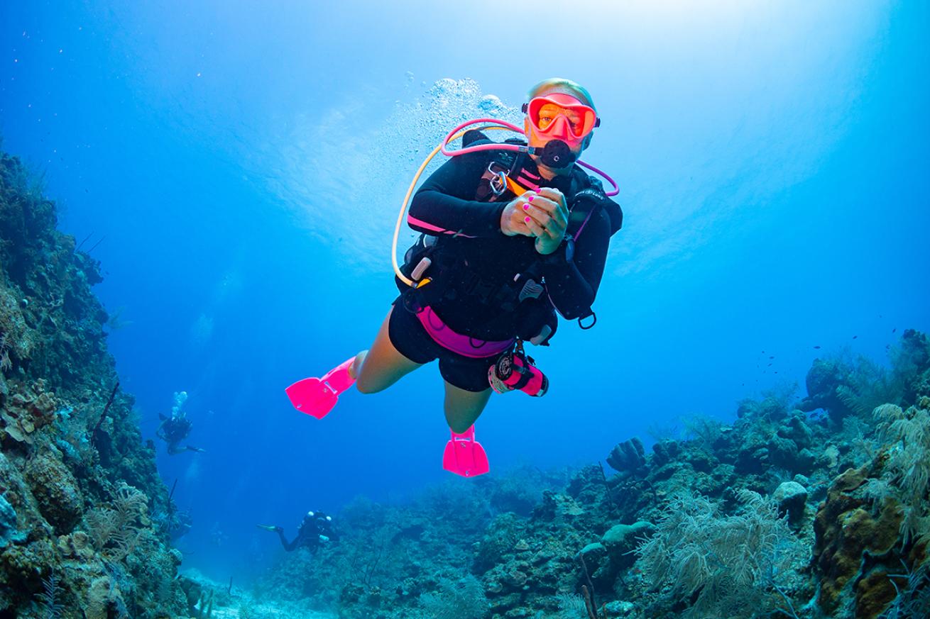 Female diver in pink fins floats near coral