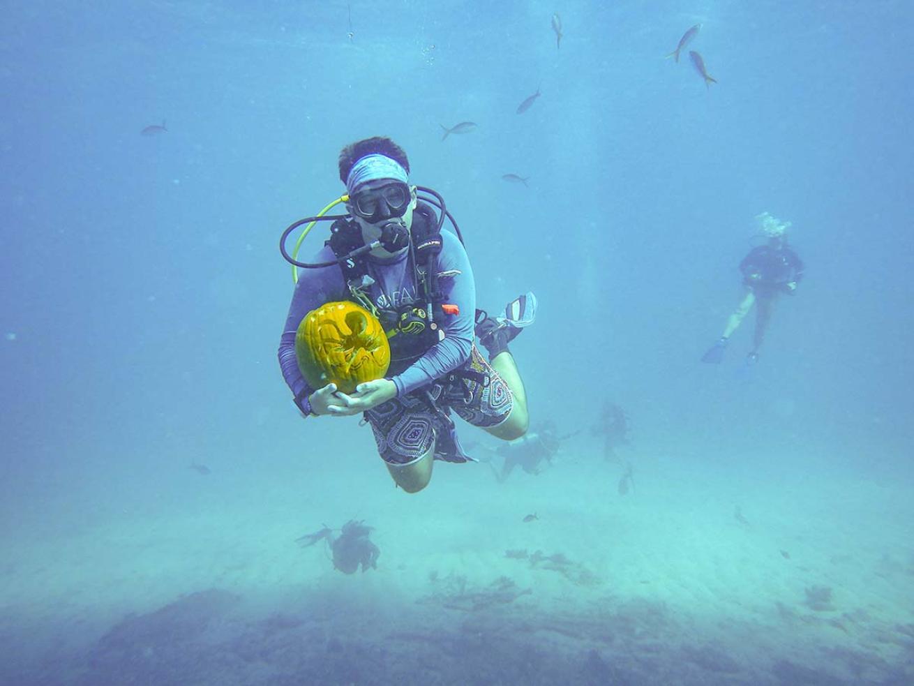 Diver underwater with jack-o-lantern