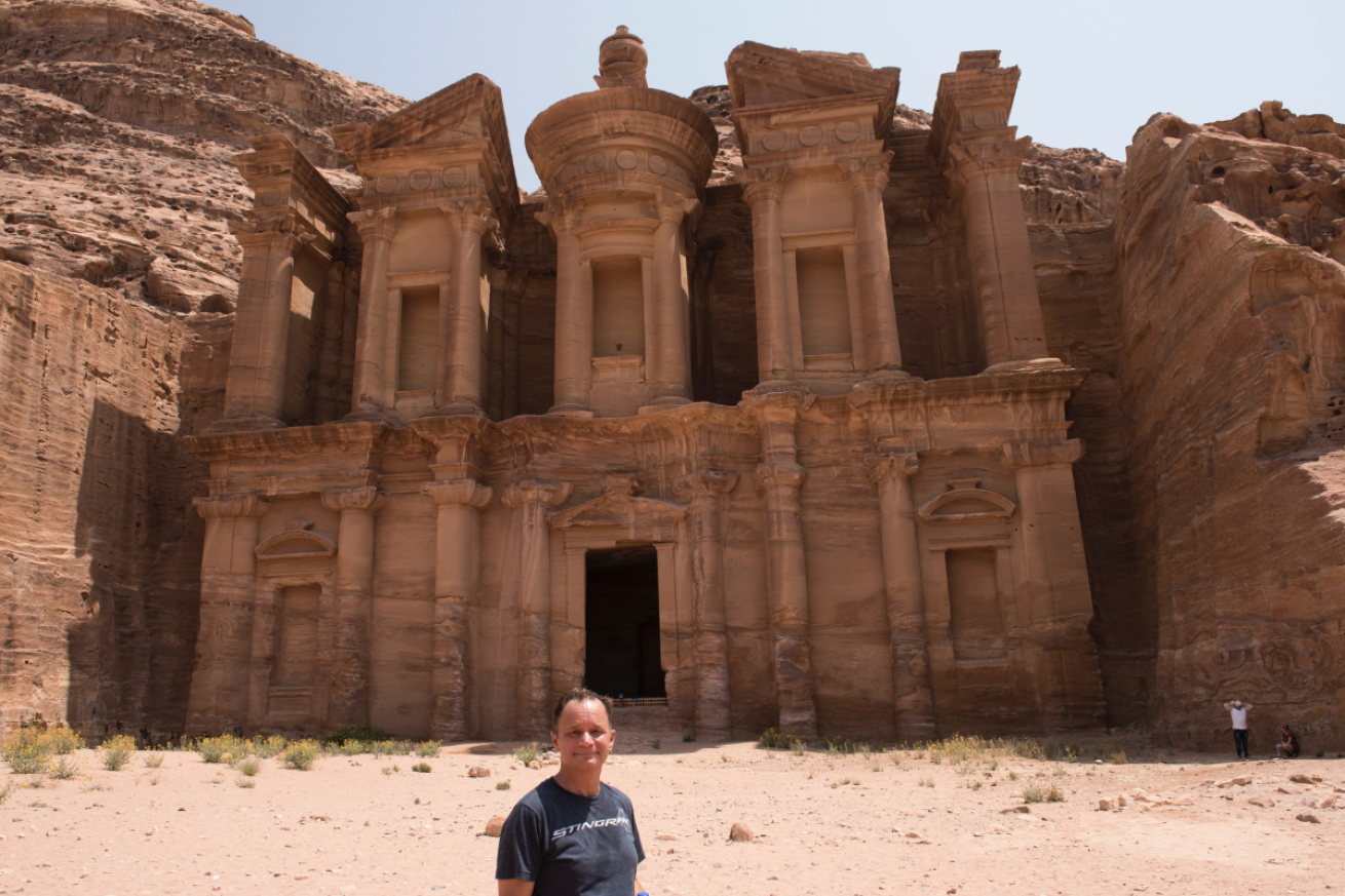 A person standing in front of a building that is carved into the rock