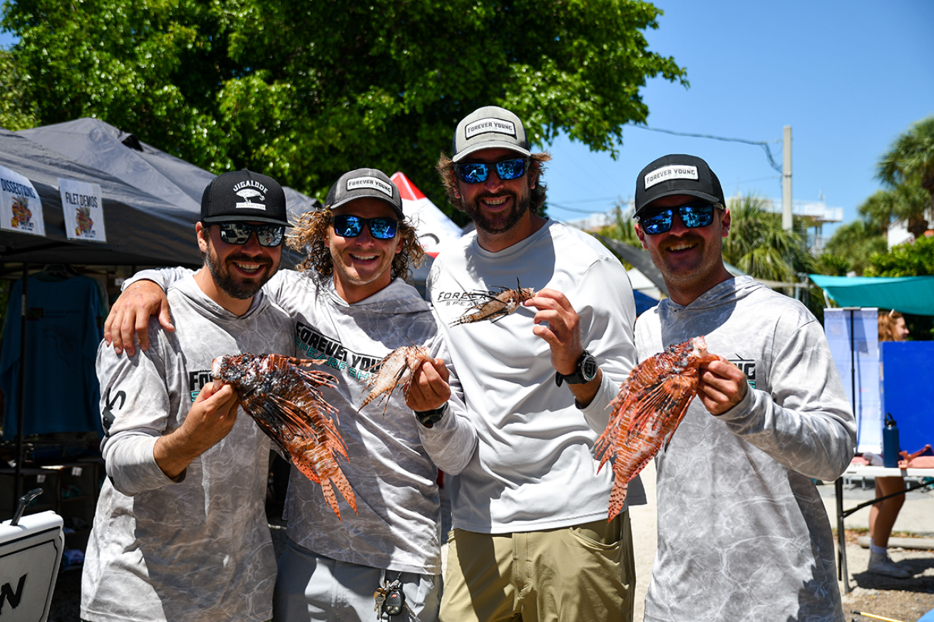 Members of the winning team holding lionfish