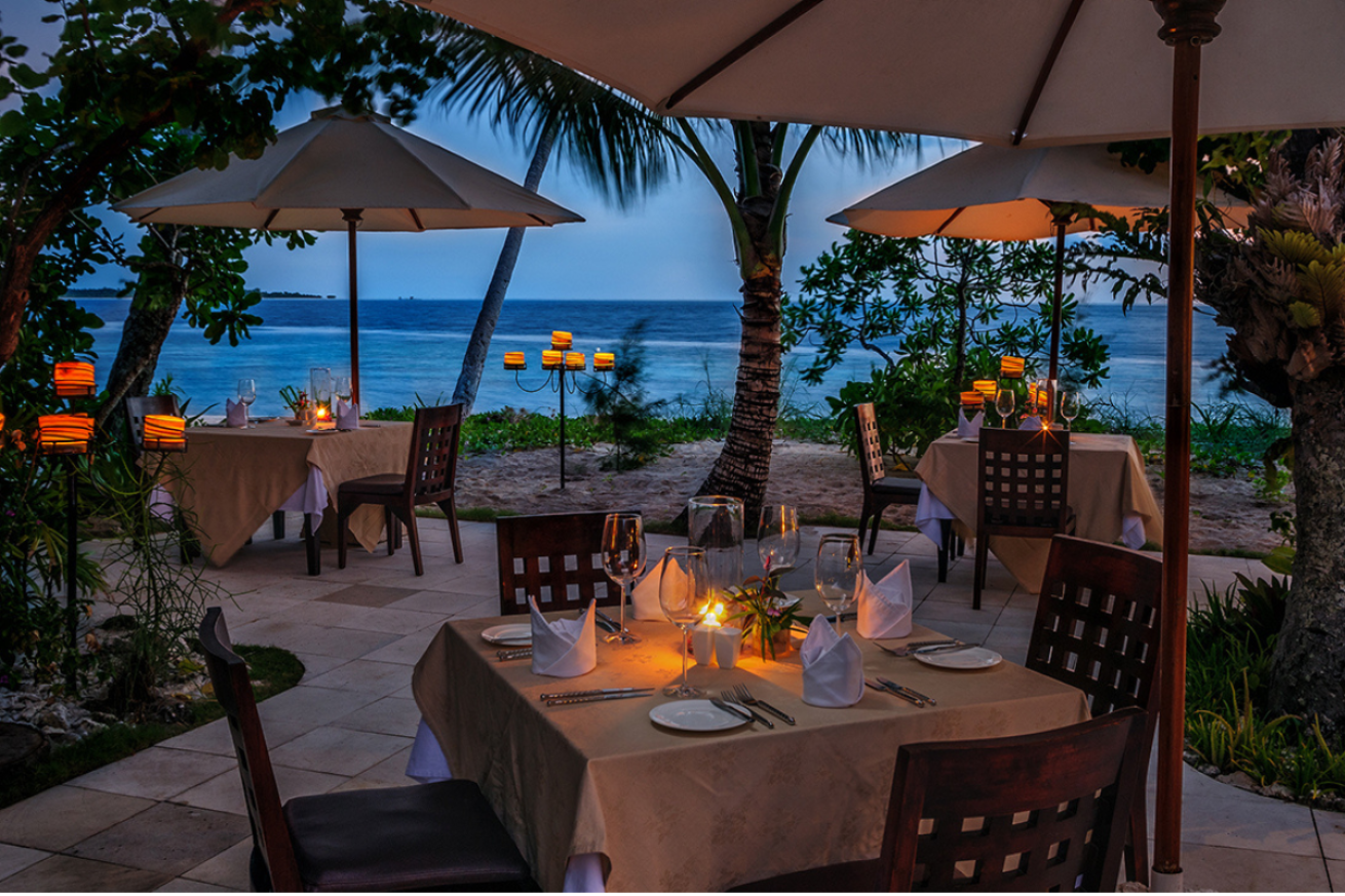 A set of tables and chairs with umbrellas by the water