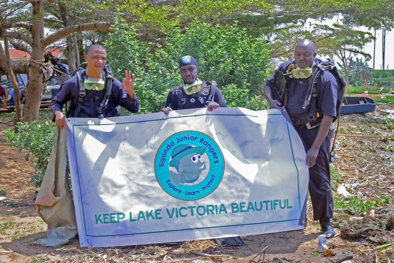 Divers hold up a Keep Lake Victoria Beautiful sign.