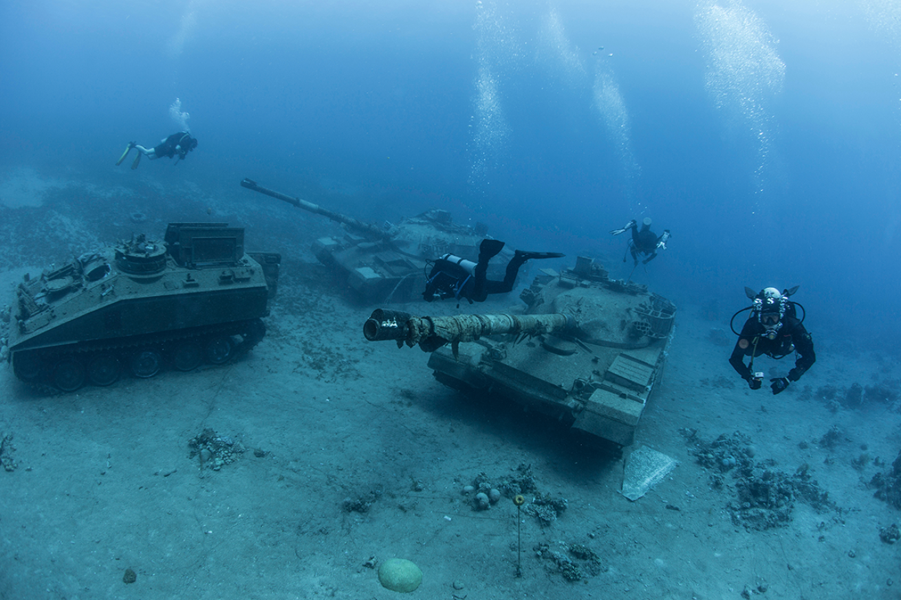 Divers discover tanks and other military machinery underwater.