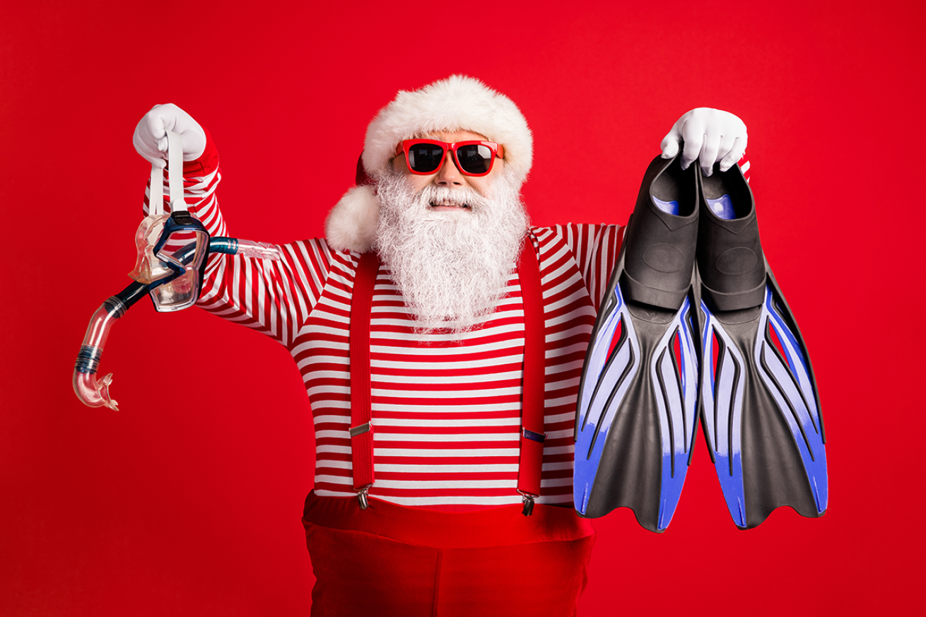 Santa Claus holding up a snorkel and fins as potential gifts.