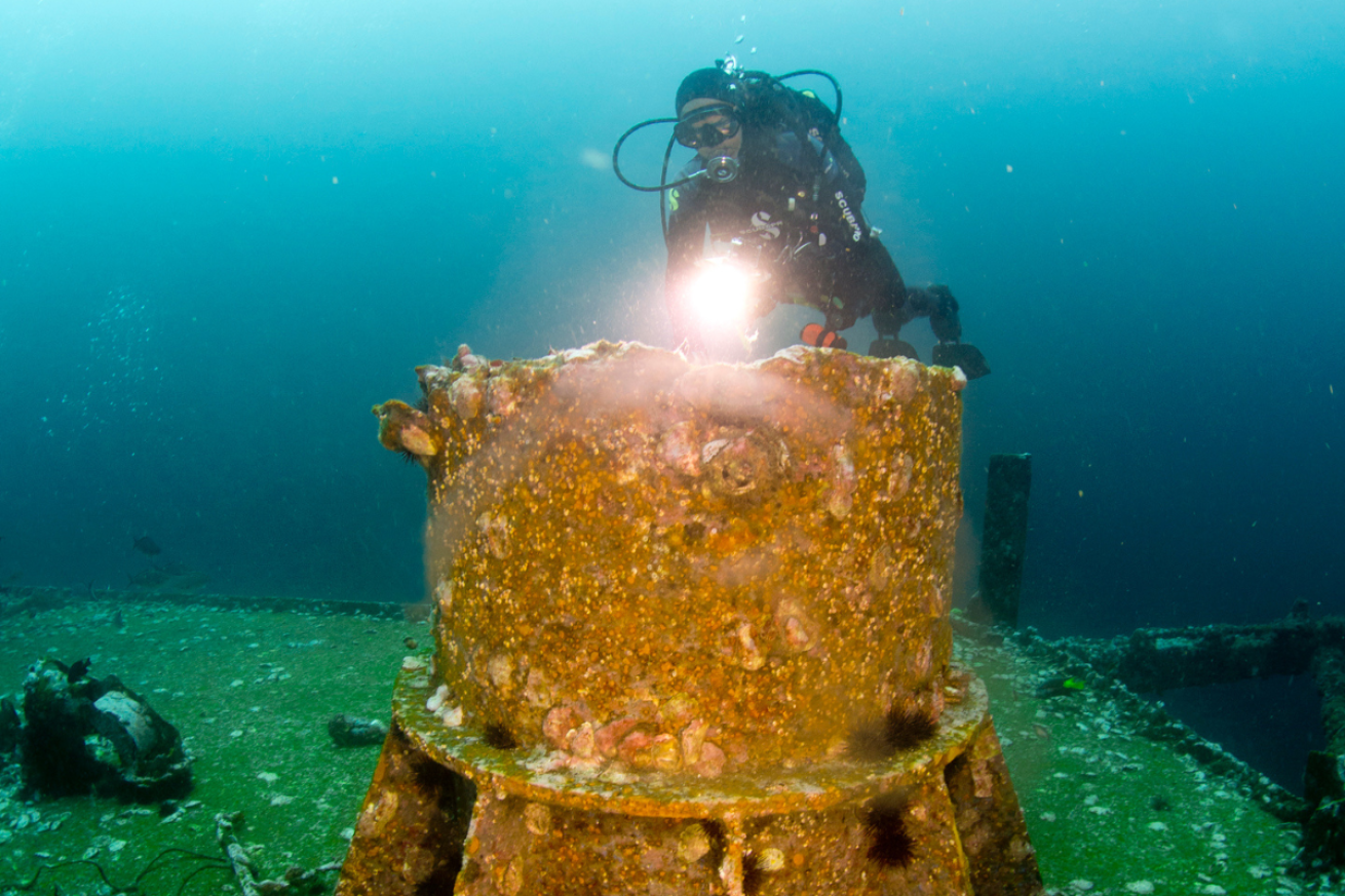 Scuba diver looking at a part of a rusted wreck