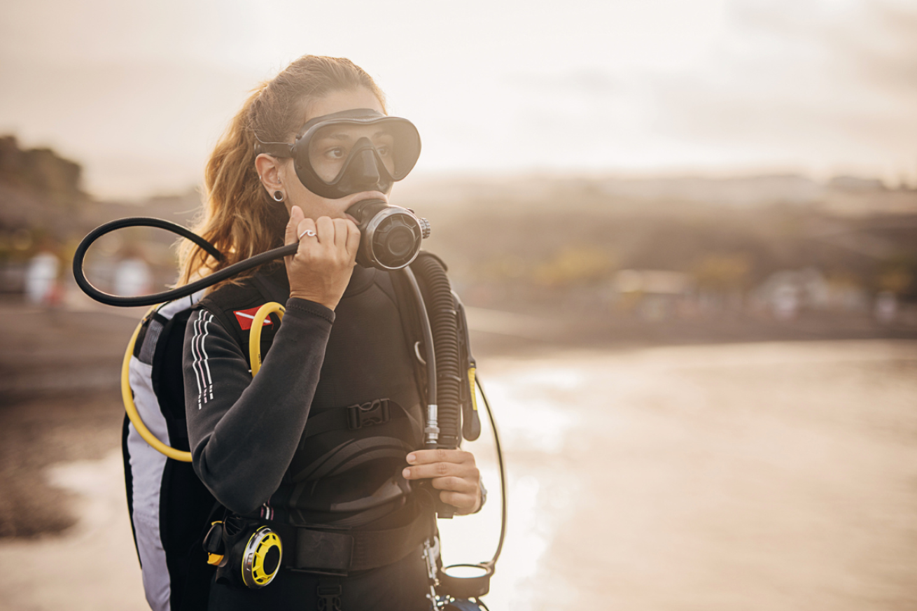 Female scuba diver testing regulator in mouth