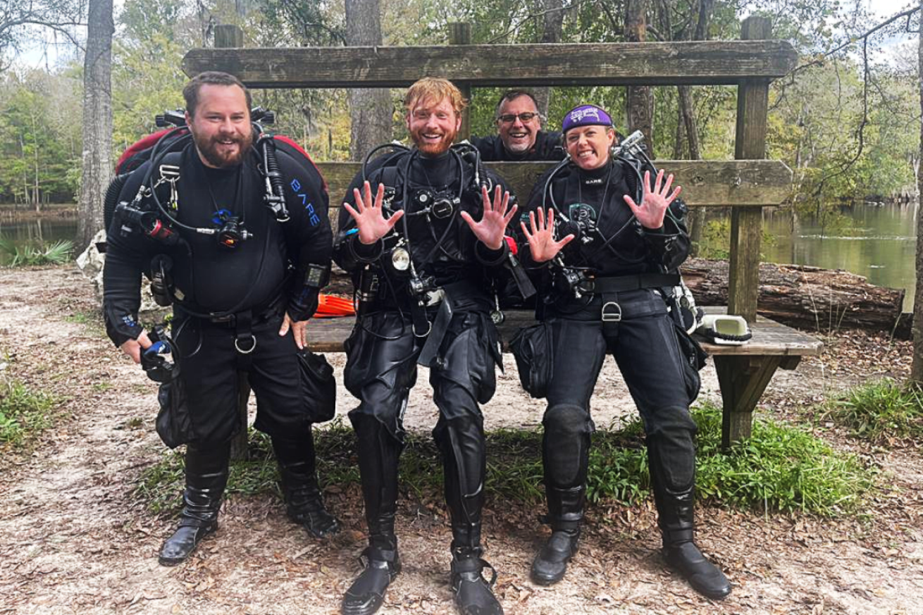 Divers posing with Ginnie Fingers after a dive