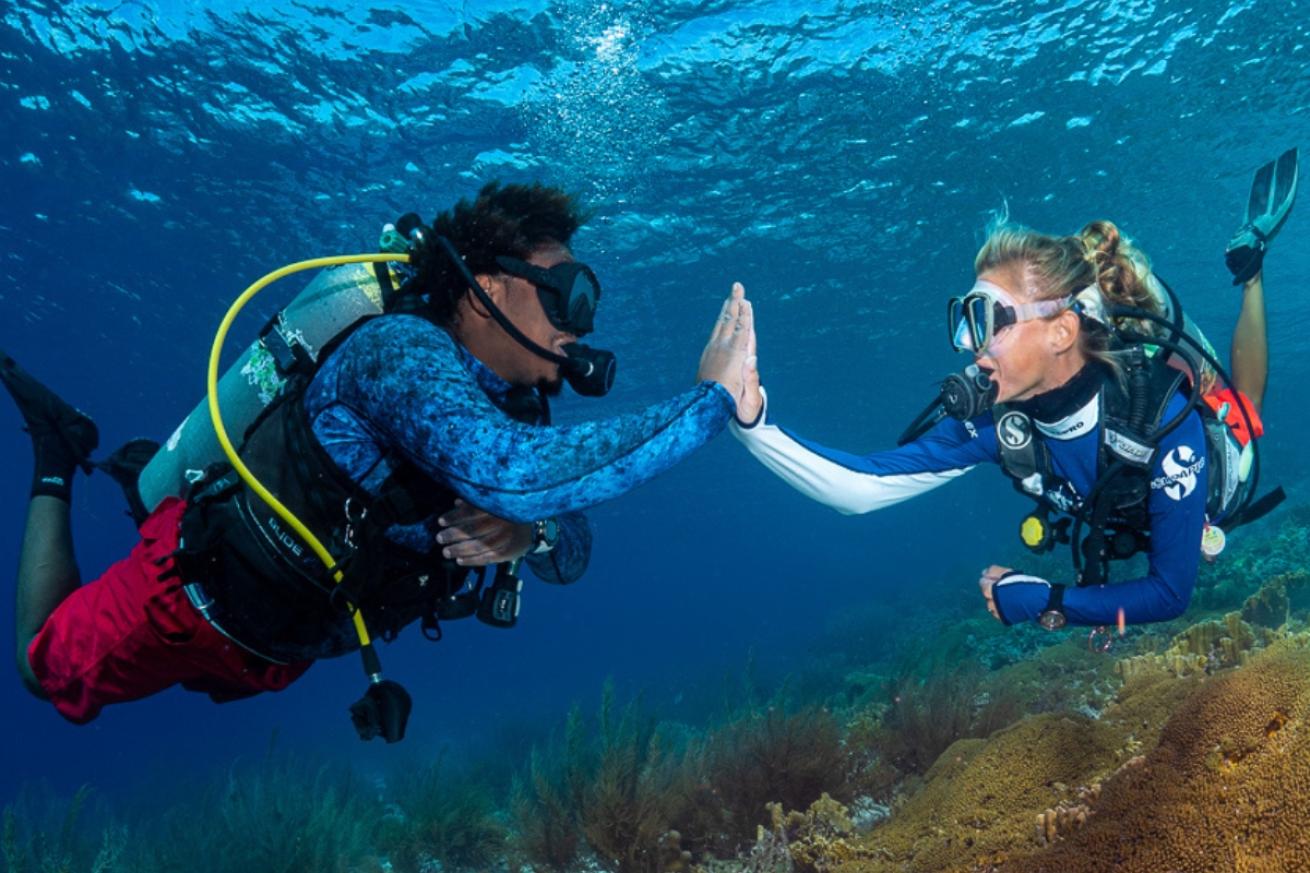 Two scuba divers high fiving underwater.