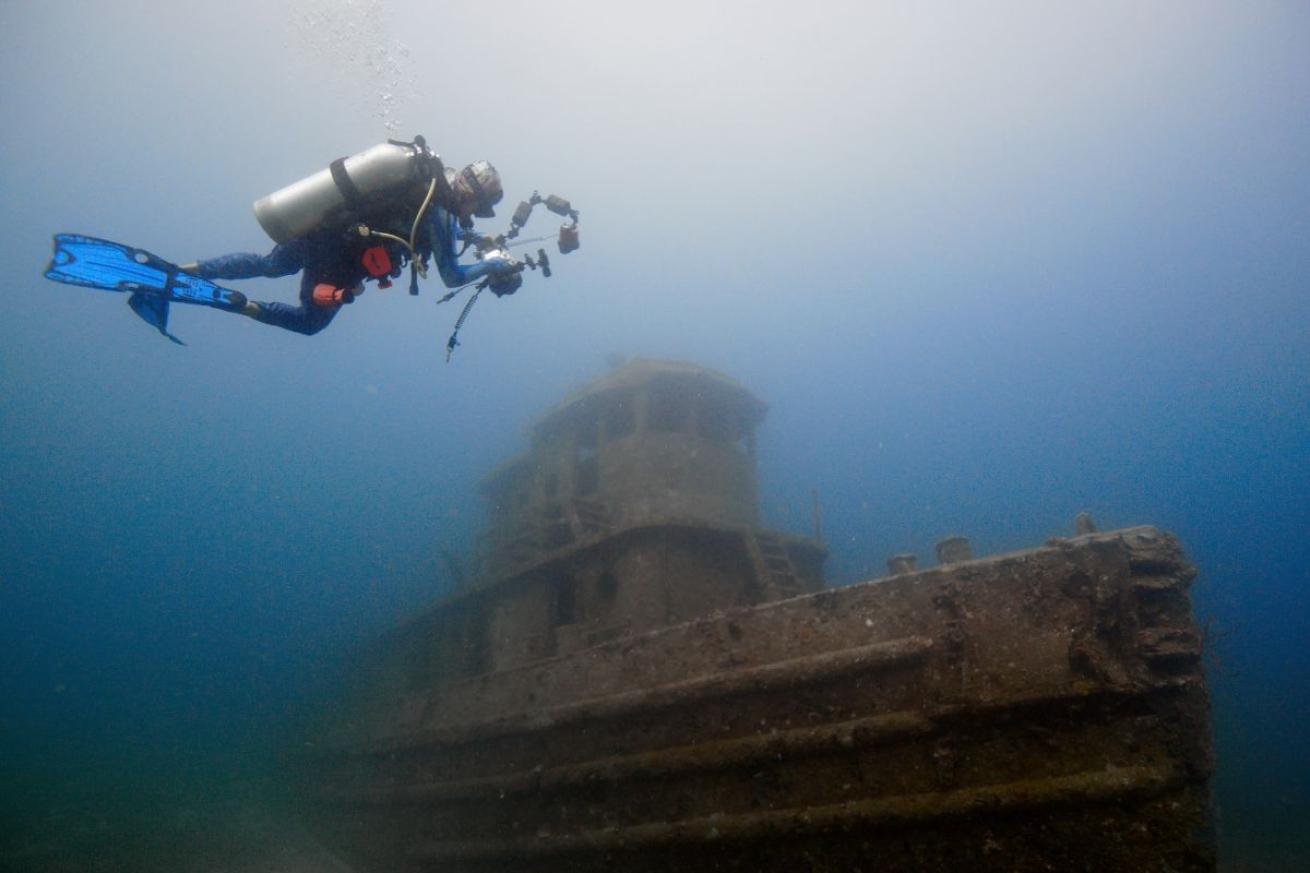 Scuba diver swimming over wreck taking a picture