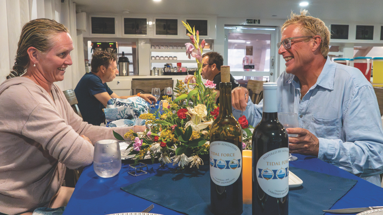 A group of people sitting at a table with wine bottles
