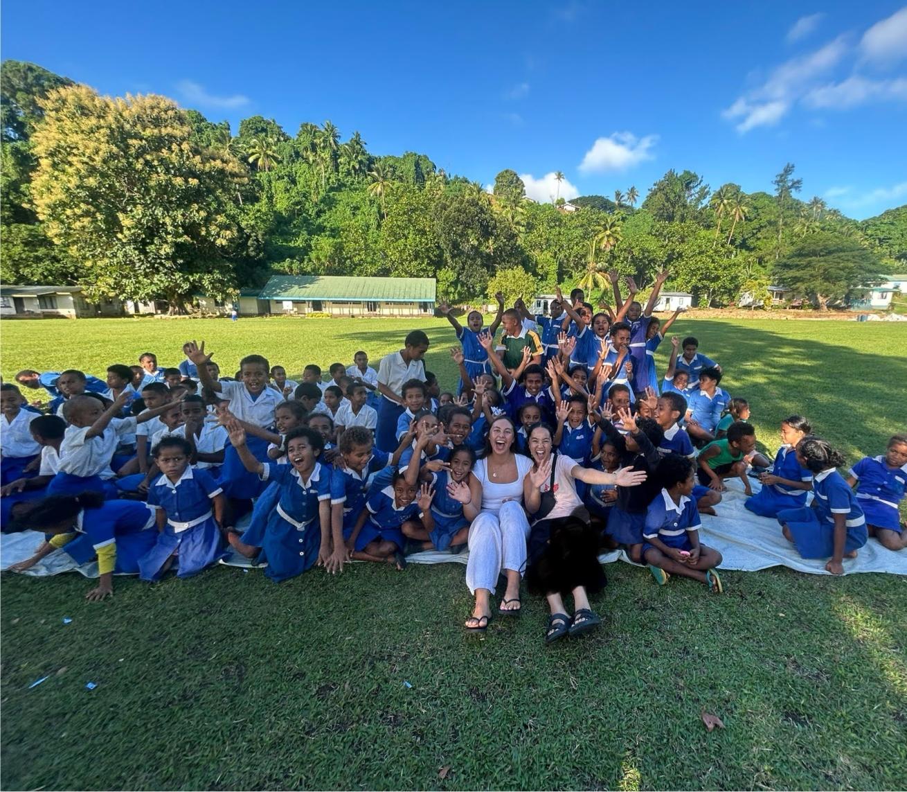 tourists pose with students at a local fijian school