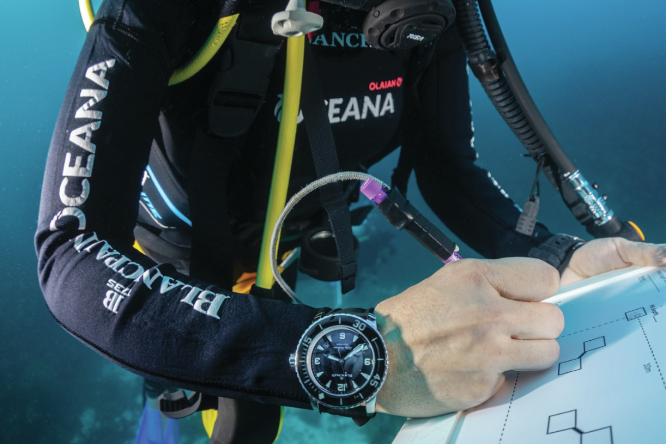 A person in a scuba diving gear writing on a board