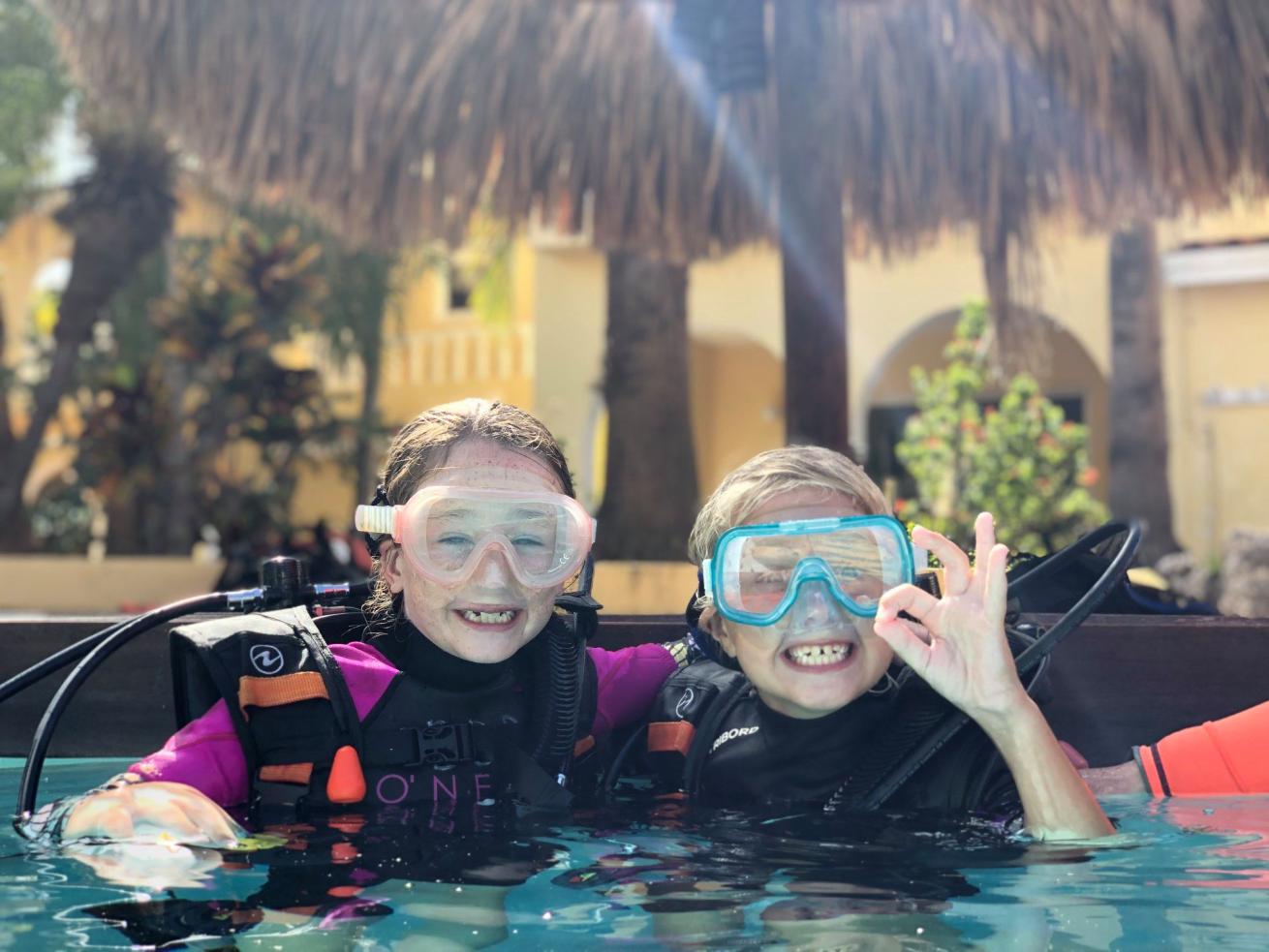 Two children wearing scuba gear in a pool