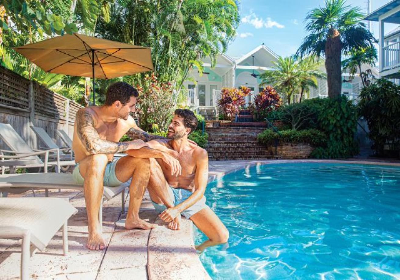 Two men sitting on a chair by a pool