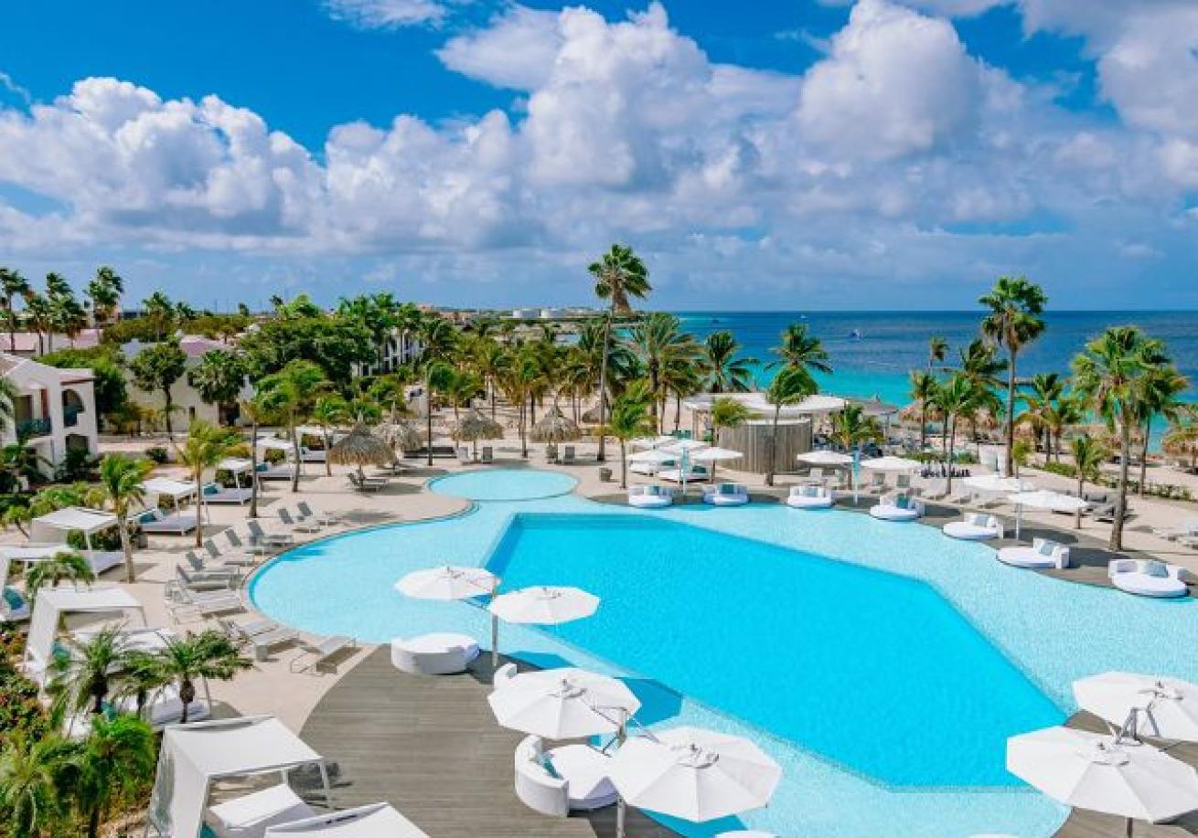 A pool with chairs and umbrellas by the ocean