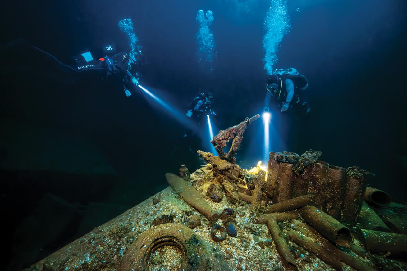 scuba divers inspect artifacts of war inside the hold of *Fujikawa Maru*.