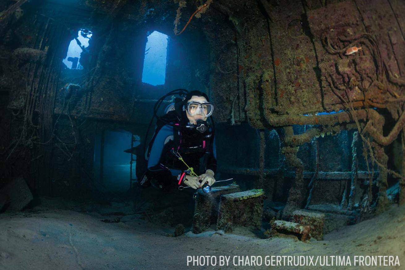 Scuba diver explores the wreck of the Doc Poulson in Grand Cayman